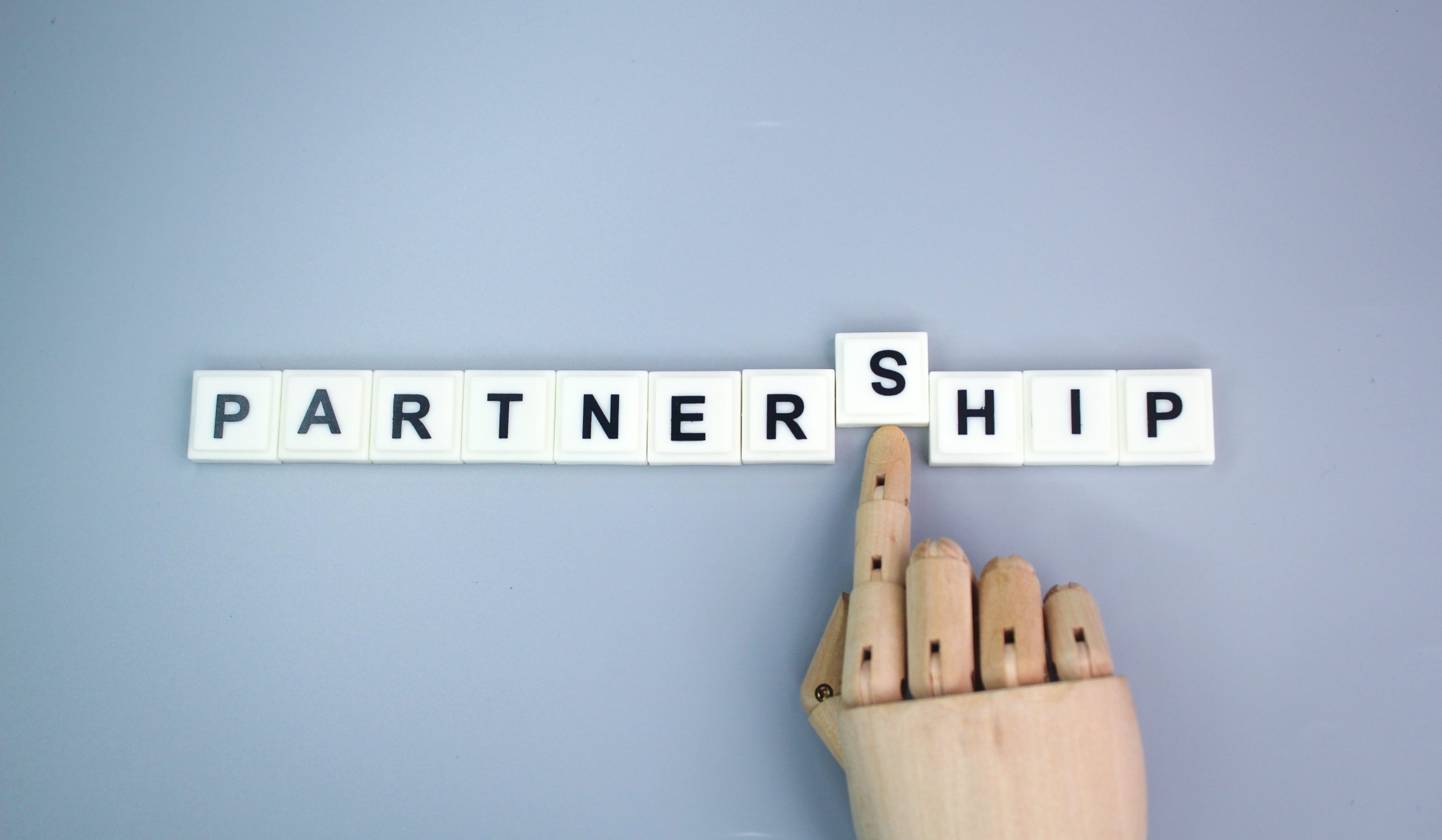 wooden hand and alphabet letters with the word partnership