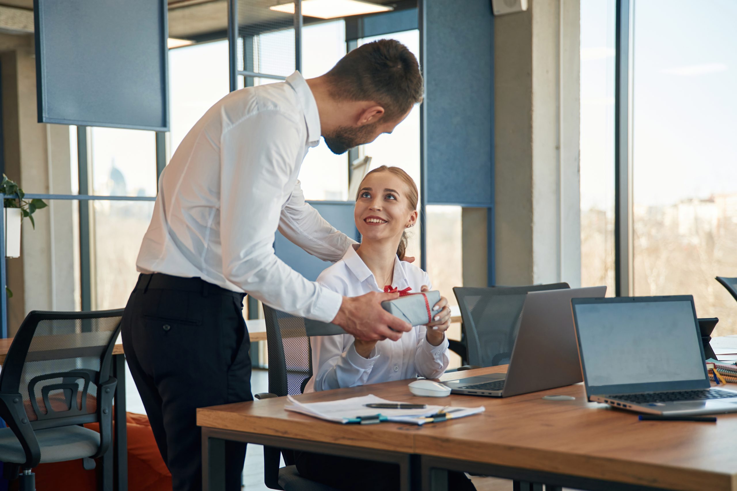 a man giving reward to female employee to enhance employee satisfaction