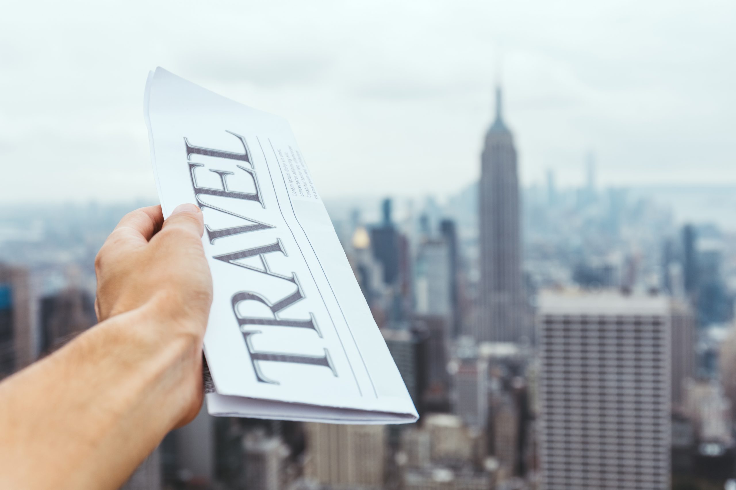 partial view of man holding travel newspaper